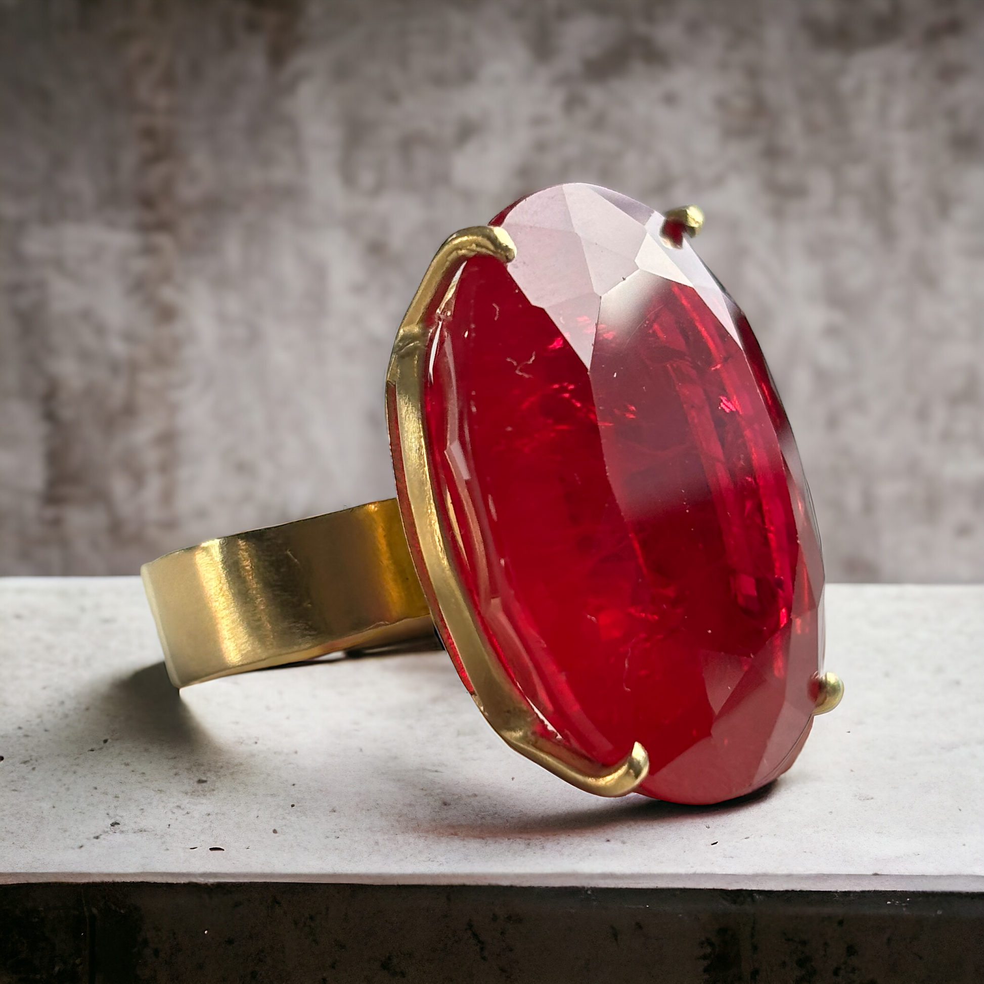18k Yellow Gold Rubellite Ring, Large Oval Rubellite and wide band ring facing right on a grey concrete countertop