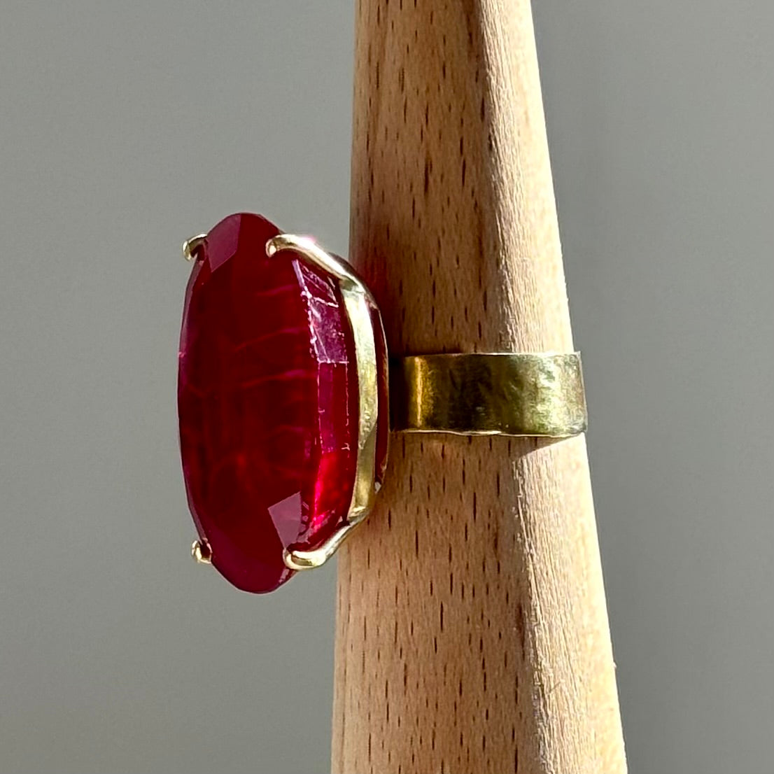 A short video Clip of an 18k Yellow Gold Rubellite Ring, Large Oval Rubellite and wide band on a wooden accessory